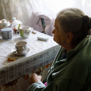 Grandmother sitting alone at a table. 